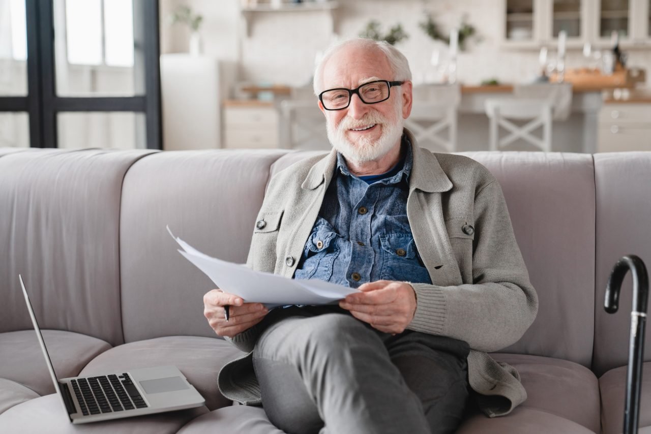 Senior man reviewing pension documents and e-banking paperwork on a laptop, reflecting Wio Accounting’s support for retirement planning, tax filing, and financial services for seniors in British Columbia.